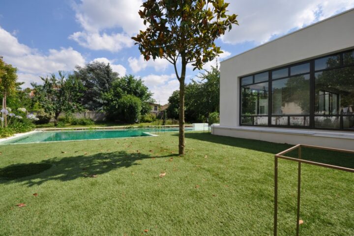 Vue extérieure d'une extension de maison haut de gamme avec piscine par AIM Projets.